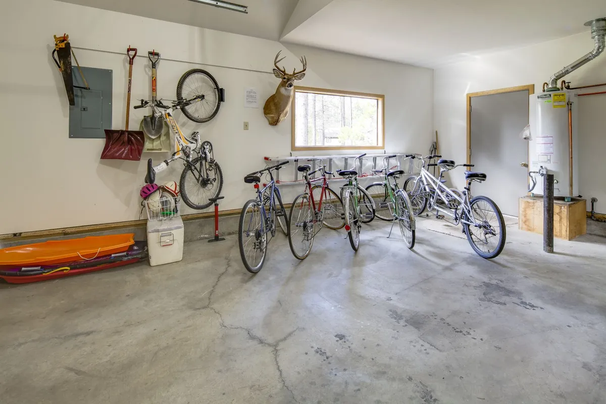 This image centers on a collection of well-maintained bicycles, a deer head mount on the wall, and various outdoor gear including shovels and ski equipment, all arranged in an organized garage space. The overall atmosphere is active and practical, emphasizing preparation for outdoor adventures and easy storage of recreational items.