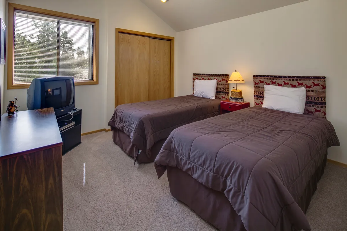 A cheerful twin bedroom with two matching twin beds, wooden furniture, and a window that bathes the space in soft, natural light. The inviting atmosphere makes it suitable for younger guests, friends, or siblings.