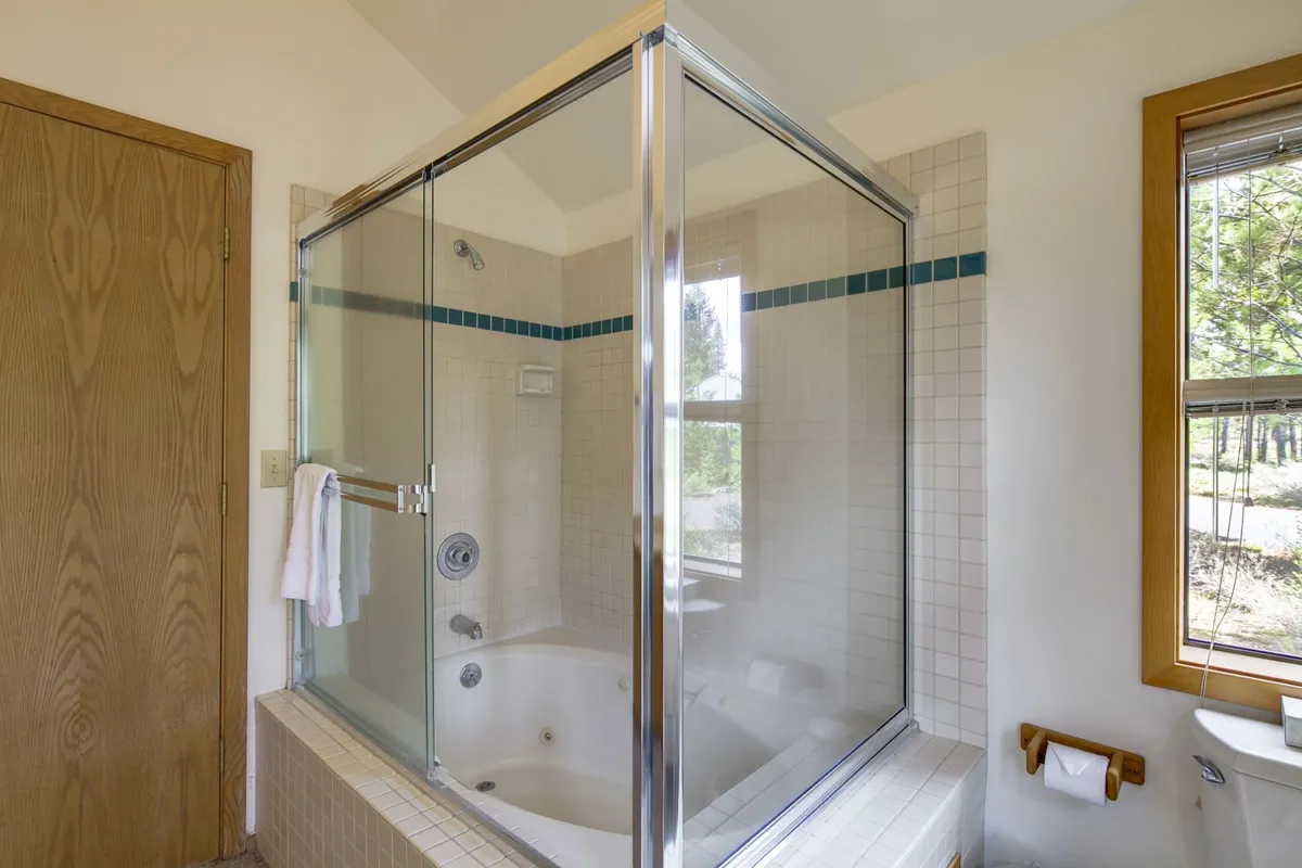 A modern bathroom featuring a spacious Jacuzzi tub, shower area, and a large window letting in ample natural light. The tranquil color palette and spa-like atmosphere evoke relaxation and rejuvenation.