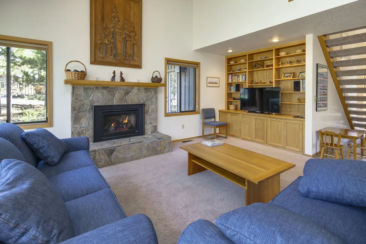 This image captures the great room with a welcoming fireplace, comfortable sofas, a bookshelf, and expansive windows. The setup is ideal for group relaxation, reading, or playing board games, aligning with the section's focus on togetherness and evening hangouts.