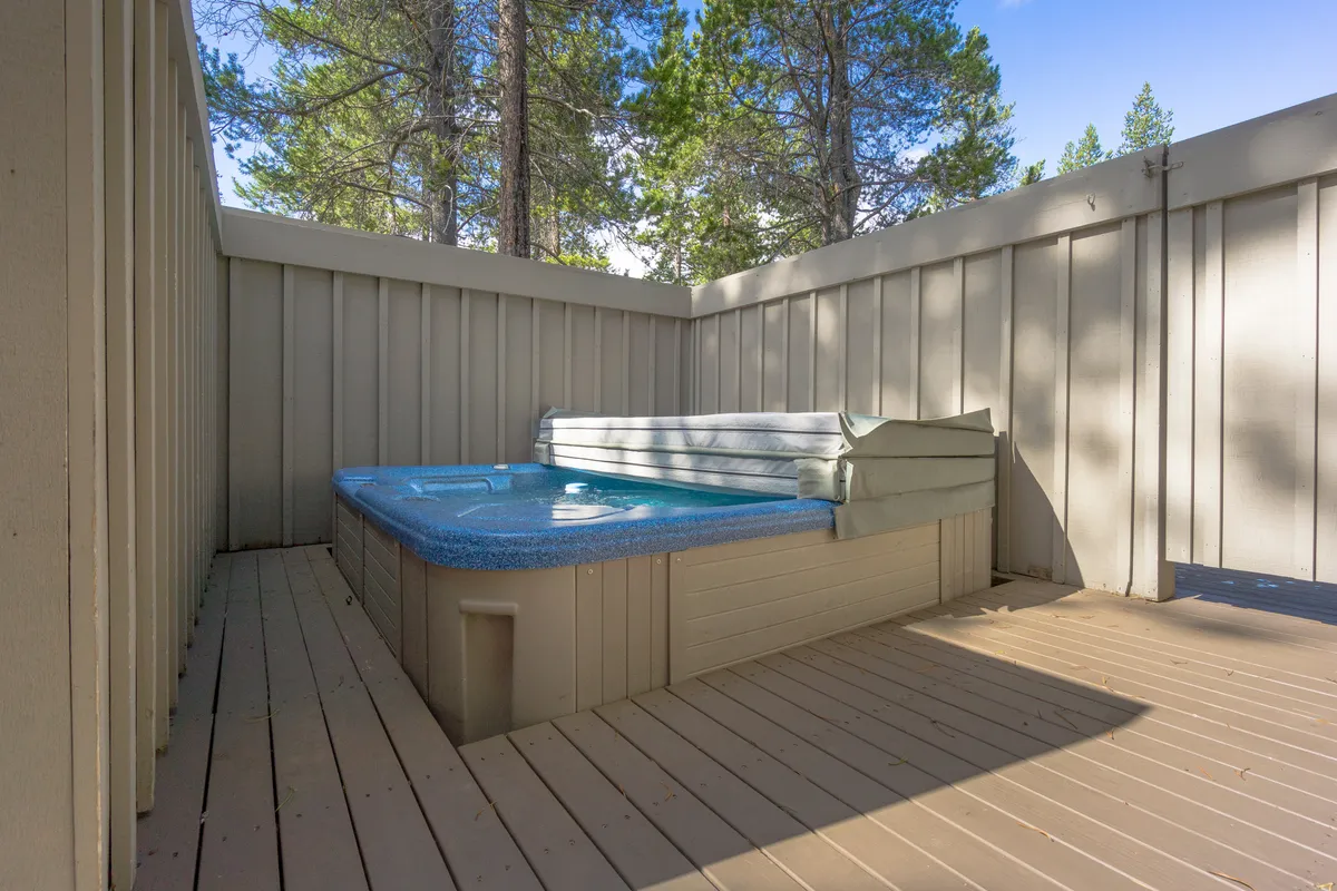 A private hot tub nestled on the deck, surrounded by tall trees, offers a tranquil escape to soak and relax in nature. The open-air design provides unobstructed views of the evening sky, ideal for stargazing or unwinding after a day of adventure.