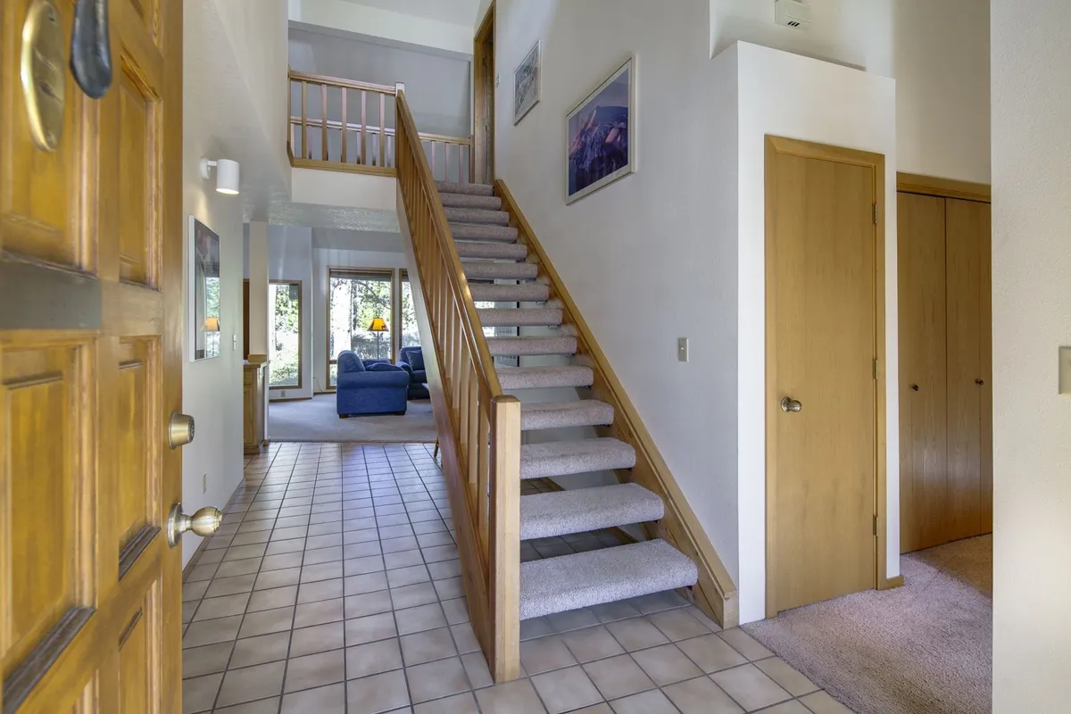 The interior view highlights an inviting living area with a blue couch, a staircase, and a welcoming entryway. The space feels open and ready for family gatherings, with ample room for shared stories and relaxing after a full day of exploration.