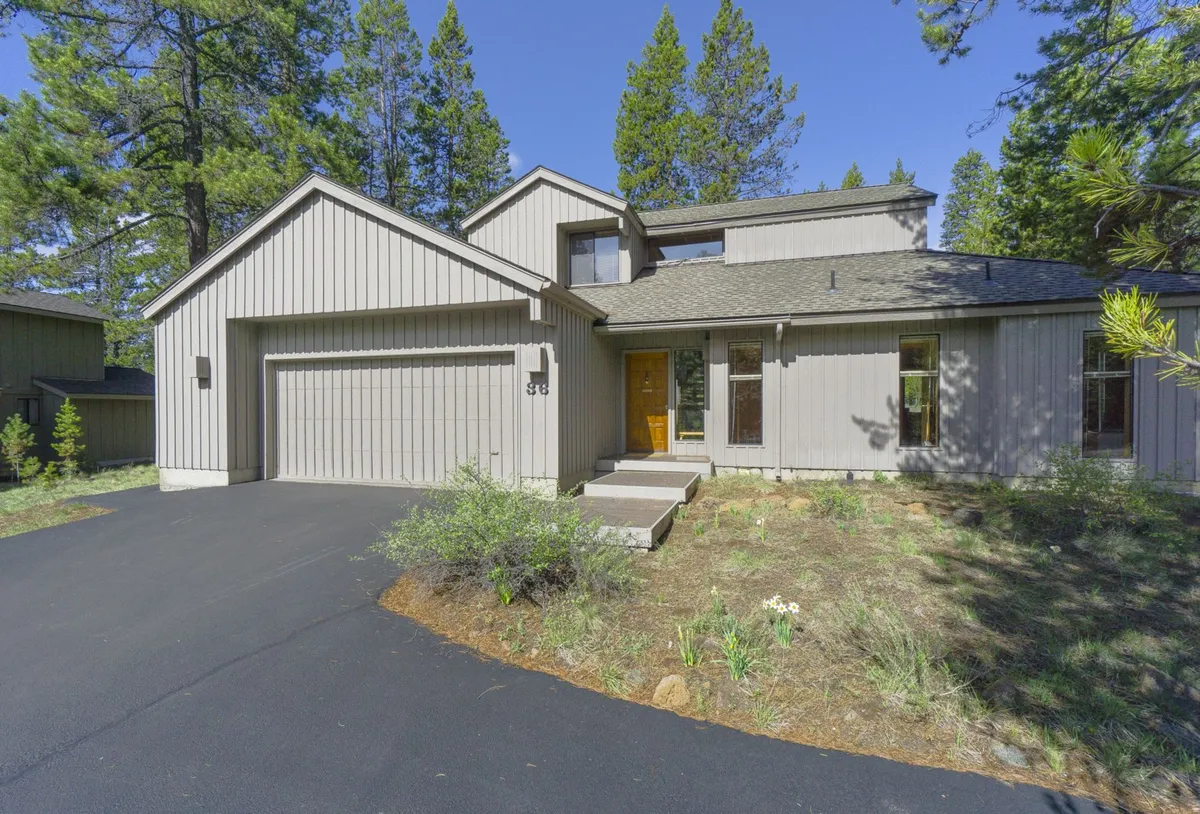 An exterior view of the home with modern architecture, highlighting the garage door, inviting front steps, and attractive landscaping. The setting feels welcoming and hints at convenient access to the garage and parking.